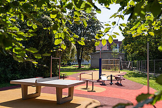 Accessible playground in Berlin-Steglitz-Zehlendorf with REGUPOL impact-absorbing safety surfacing, fitness equipment, table tennis facilities, and an inclusive play and recreation area for children, families, and adults.