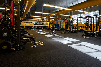 Millersville University Performance Center - Weight Room View of the Millersville strength center offered to athletes to continue improving their athletic performance. A number of weight racks are available to athletes, allowing for a variety of exercises to be performed. REGUPOL aktivpro roll flooring is featured throughout the facility.