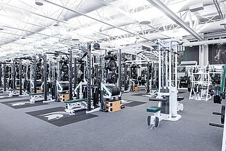 Michigan State Football Weight Room - Weight Racks and Machines The weight racks and lateral pulldown machines available in the Michigan State football weight room. A number of different machines are located in the background of the image as well. All equipment rests on REGUPOL aktivpro roll flooring.