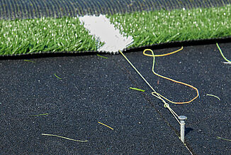 Spring Grove Area High School - Turf Installation with REGUPOL abzorb The turf at Spring Grove Area High School being tied into REGUPOL abzorb. The view shows a part of the installation process.
