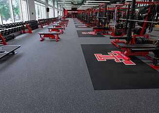 Texas Tech Olympic - Free Weights & Racks View of the side of the Texas Tech Olympic room that features free weights and benches, as well as weight racks.