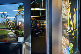 Millersville University Performance Center - Doorway into Facility Doorway into the Millersville University Performance Center. The glass doors have the Millersville logo featured on the doors and a view of the performance center can be viewed. The space utilizes REGUPOL aktivpro roll flooring throughout the facility.