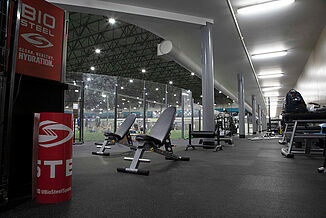 Kelowna High Performance - Two Weight Benches on REGUPOL aktiv Flooring Two weight benches and various other athletic equipment sits on REGUPOL aktiv rolled rubber flooring in Kelowna High Performance. The REGUPOL flooring surrounds the turf area of the facility and provides a seamless flooring for weight training purposes.