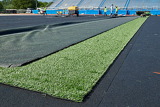 Spring Grove Area High School - Installation of Turf with REGUPOL abzorb REGUPOL abzorb synthetic turf shock pad is installed beneath the turf at Spring Grove Area High School. The view shows the installation as the turf is placed on the shock pad.