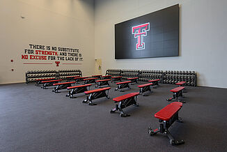 Texas Tech Football - Free Weights The free-weight area of the Texas Tech Football weight room, featuring a number of benches and a vast amount of dumbbells for athletes.
