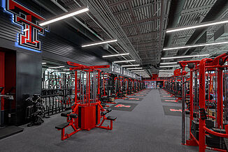Texas Tech Olympic - Machinery & Weight Racks Far view of Texas Tech Olympic room, showcasing the machinery and cables that are offered to athletes. The variety of equipment allows athletes and trainers to conduct a number of specific exercises.