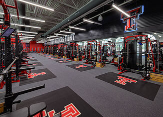 Texas Tech Olympic - Weight Racks View of the Texas Tech Olympic Weight Room, offering a number of weight tracking racks for athletes to perform workouts to strengthen their performance.