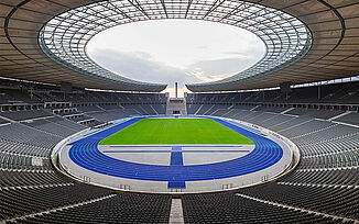 Berlin Olympic Stadium with blue running track – the Blue Miracle. View of the empty athletics arena. Berlin Olympic Stadium with empty interior and iconic blue synthetic running track, known as “the Blue Miracle.” A world-class athletics venue for national and international track and field events.