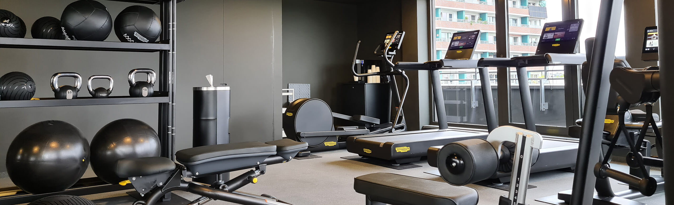 Sana Hotel fitness studio in Berlin. Equipped with treadmills, weight benches and other fitness equipment. The flooring is a light-colored elastic REGUPOL fitness floor.