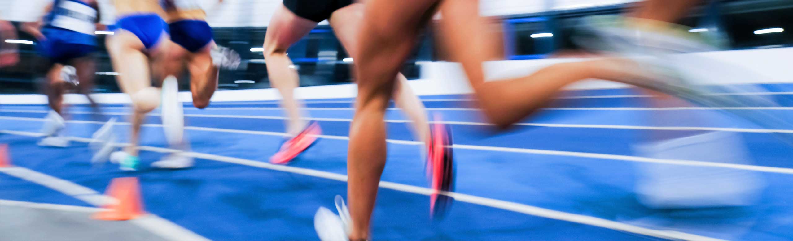 Dynamic image of an athletics race, female runners sprinting on a blue track, motion
