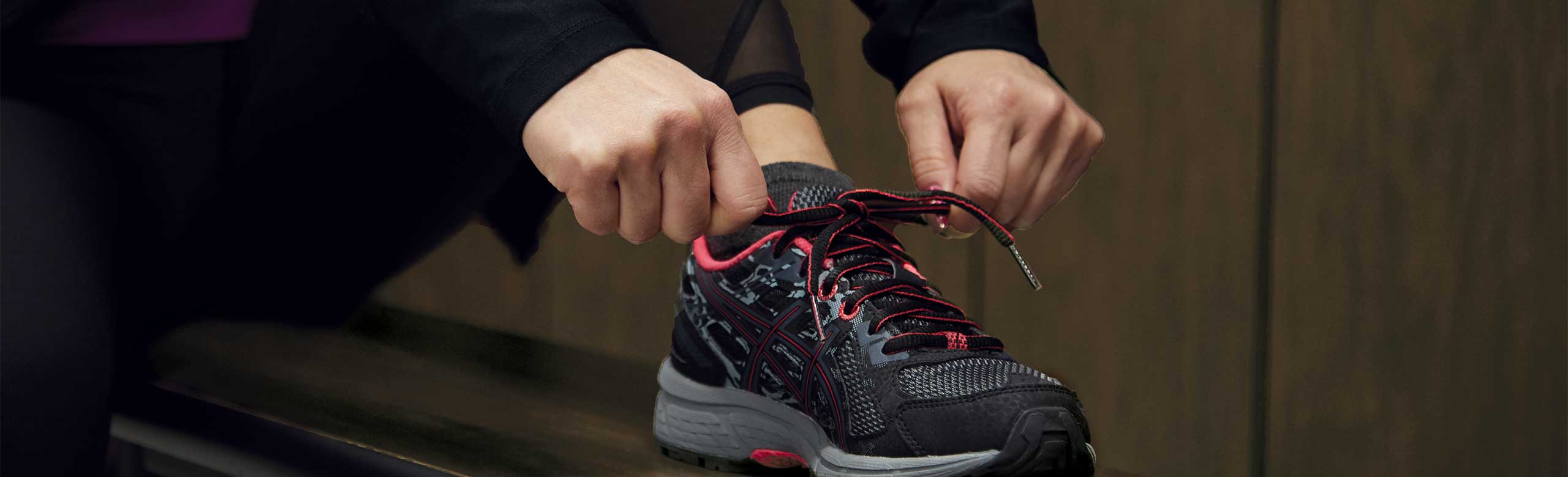 A person ties a shoe on a bench in a changing room. A person ties a shoe on a bench in a changing room.