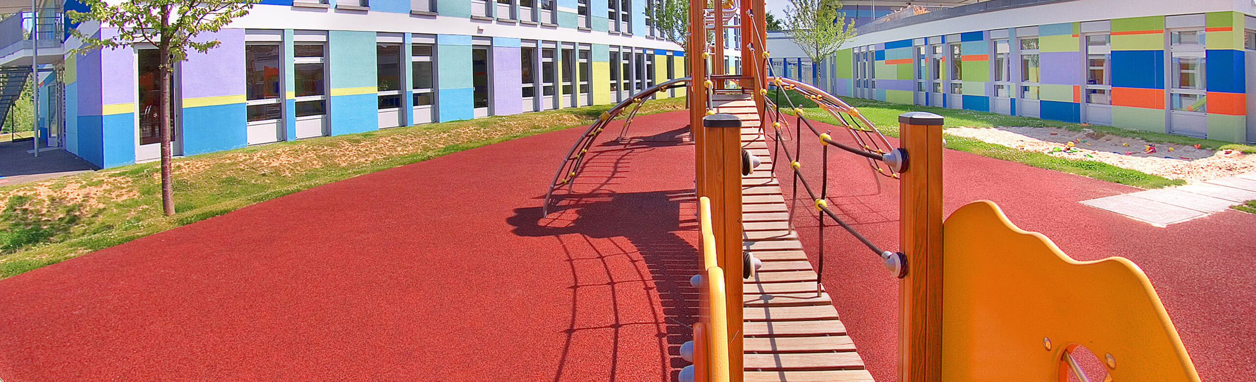 REGUPOL playfix safety flooring for playgrounds. Playground with a red safety flooring from REGUPOL