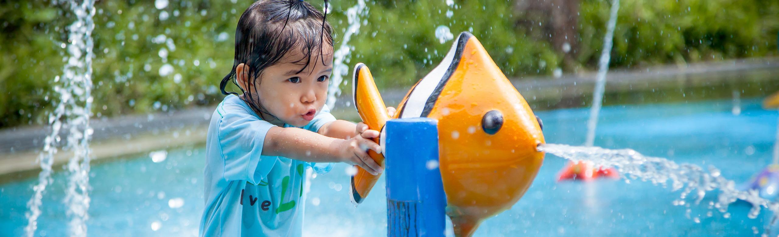 Slip-resistant safety flooring in wet areas from REGUPOL. Child playing on water playground with REGUPOL playfix safety flooring
