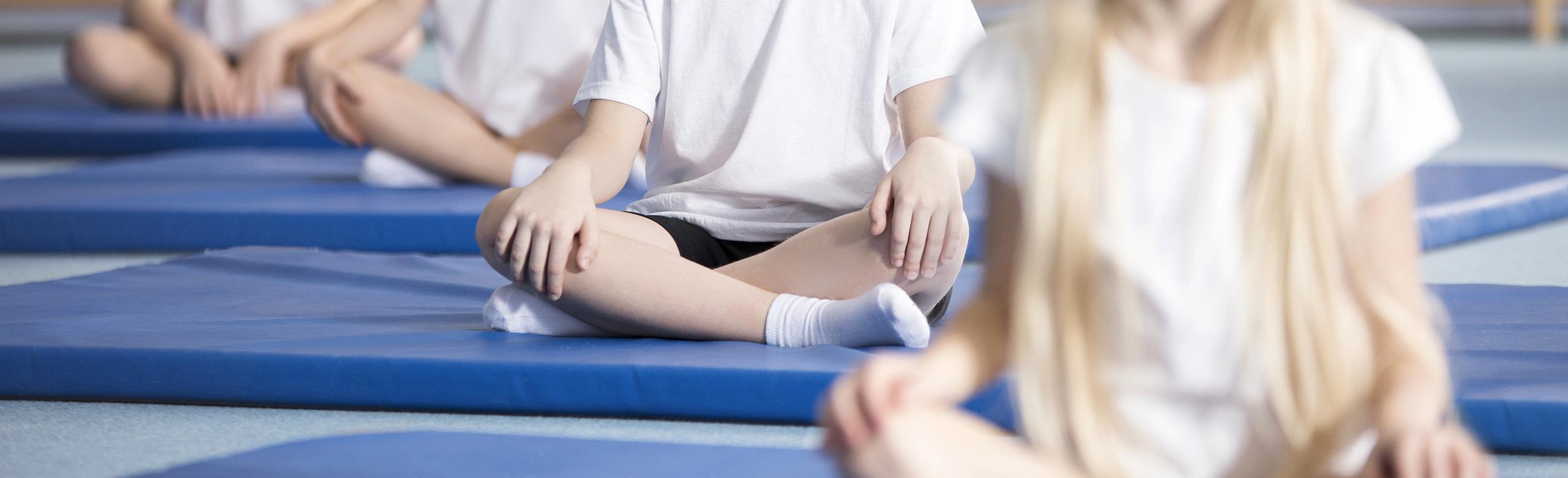 Children sit on blue sports mats Children sit in a relaxed position on sports mats.