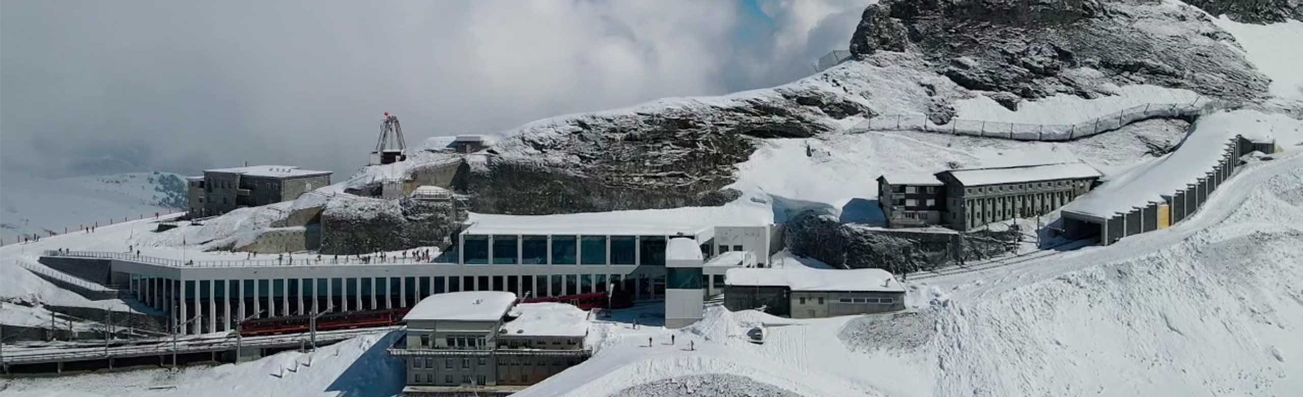Exterior view of a mountain railway station. The mountain station is located on a mountain. The mountain and the mountain station are covered in snow.