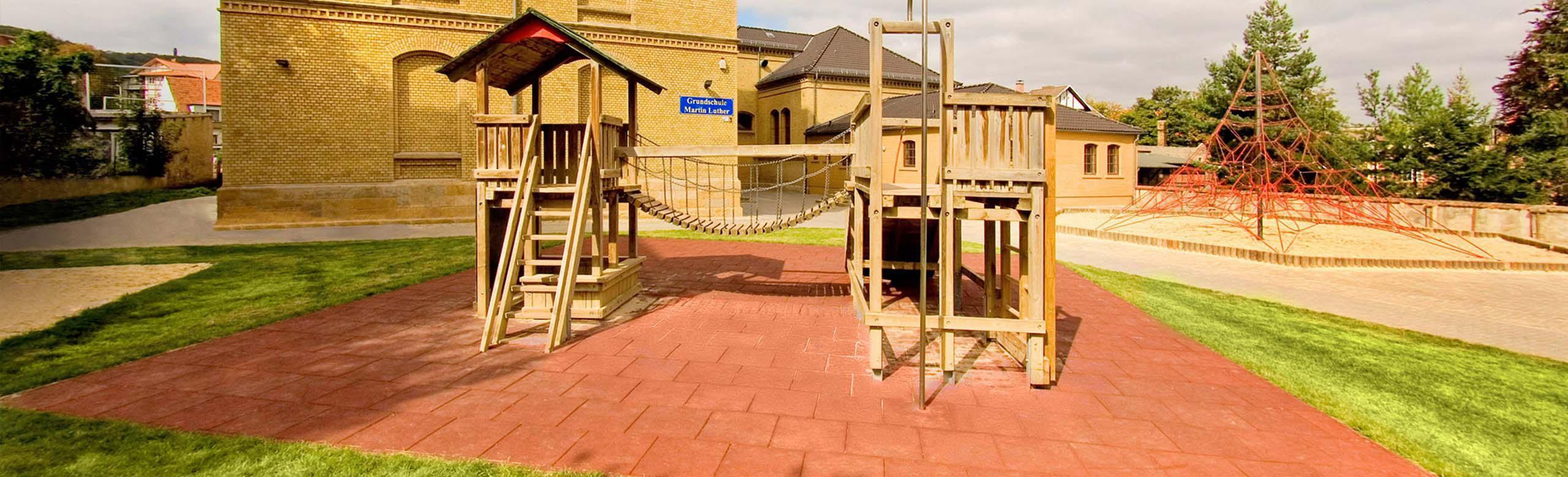 Playground with REGUPOL playfix safety flooring in red, equipped with climbing frame - ideal surface for safe outdoor play.