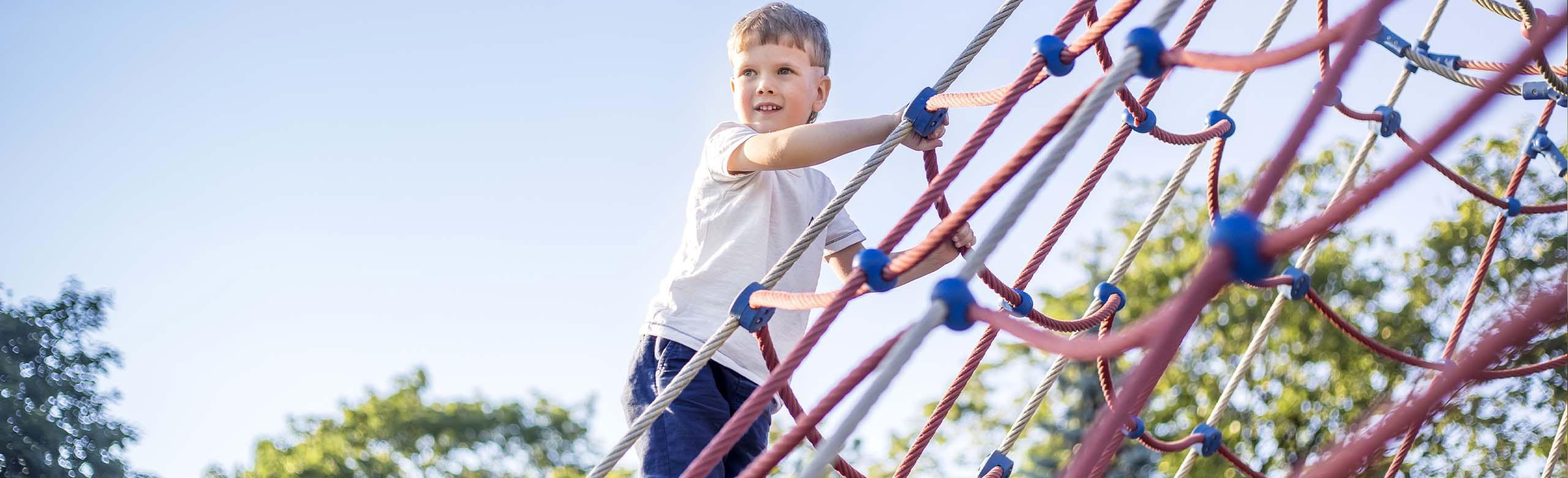 A child climbs on a playground with REGUPOL playfix safety flooring