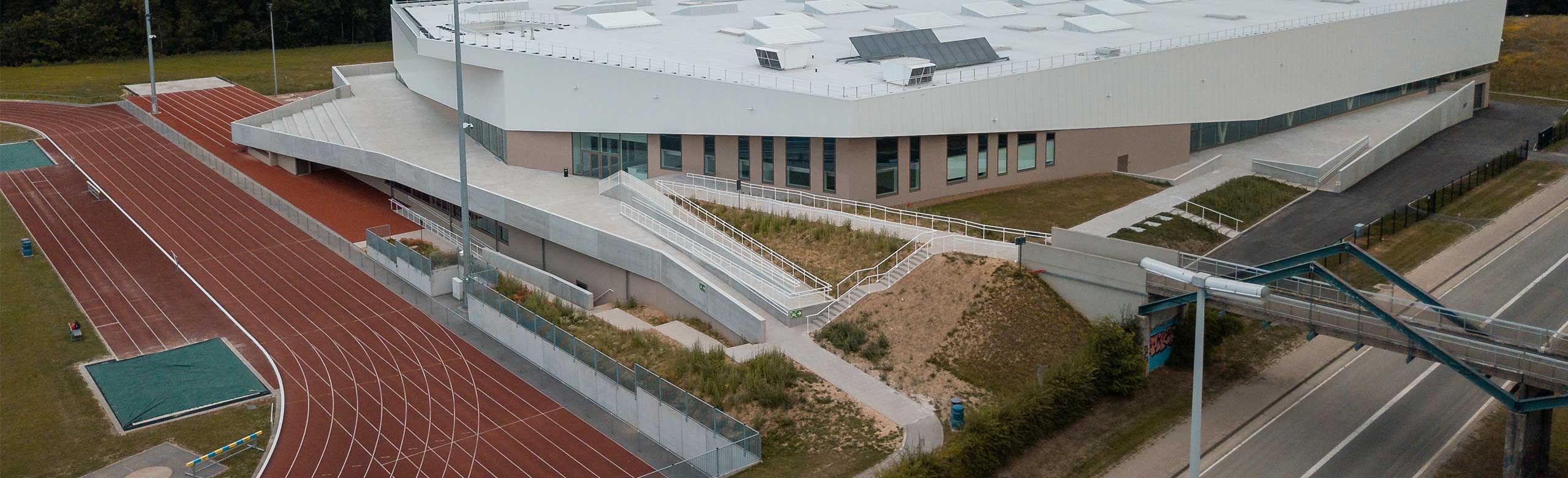 Modern athletics hall from the outside, with visible part of a red sprint track. Athletics hall with sprint track in Louvain-la-Neuve, exterior view