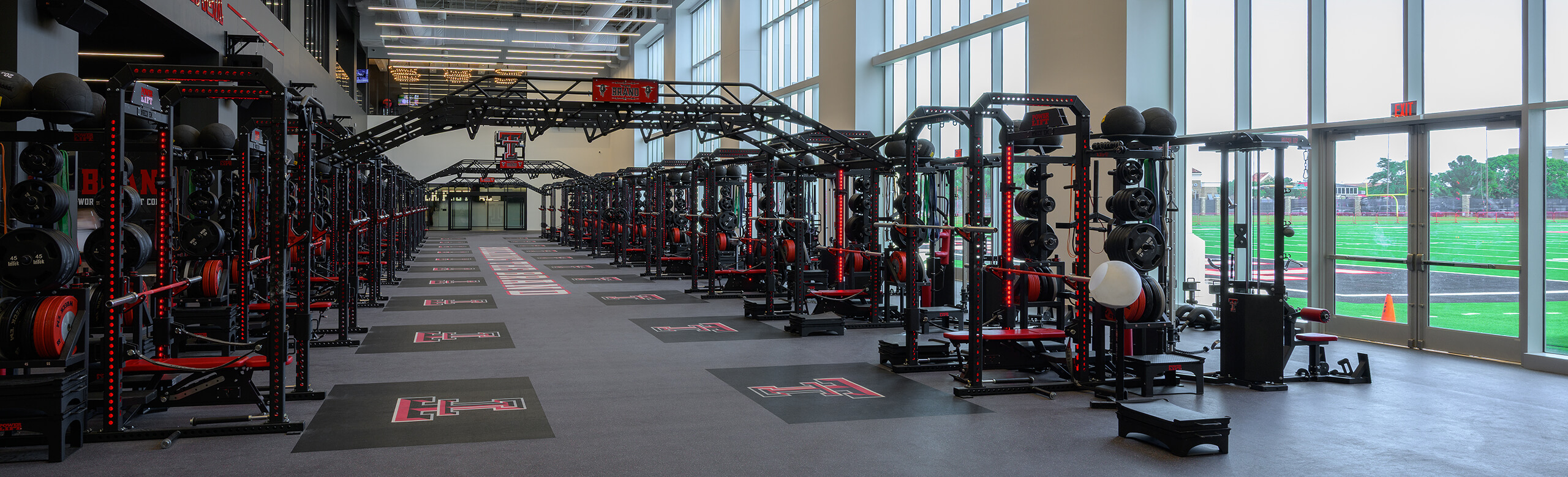 Texas Tech Football - Banner View of entrance of Texas Tech Football weight room, showcasing the number of weight training racks and REGUPOL crash platforms.